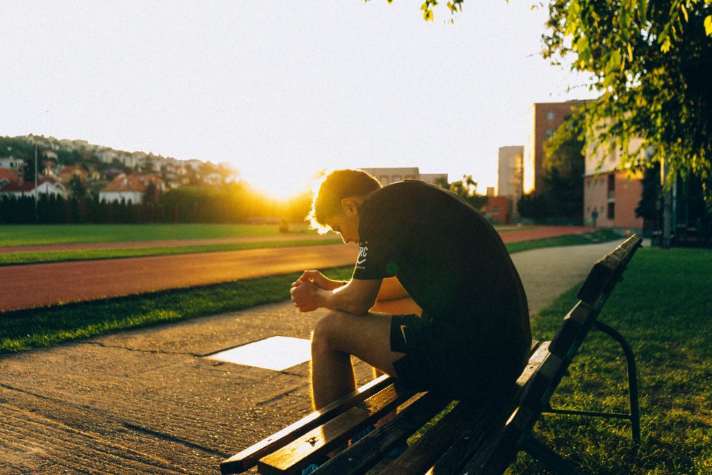 athlete sitting on a bunch at the time of sunset